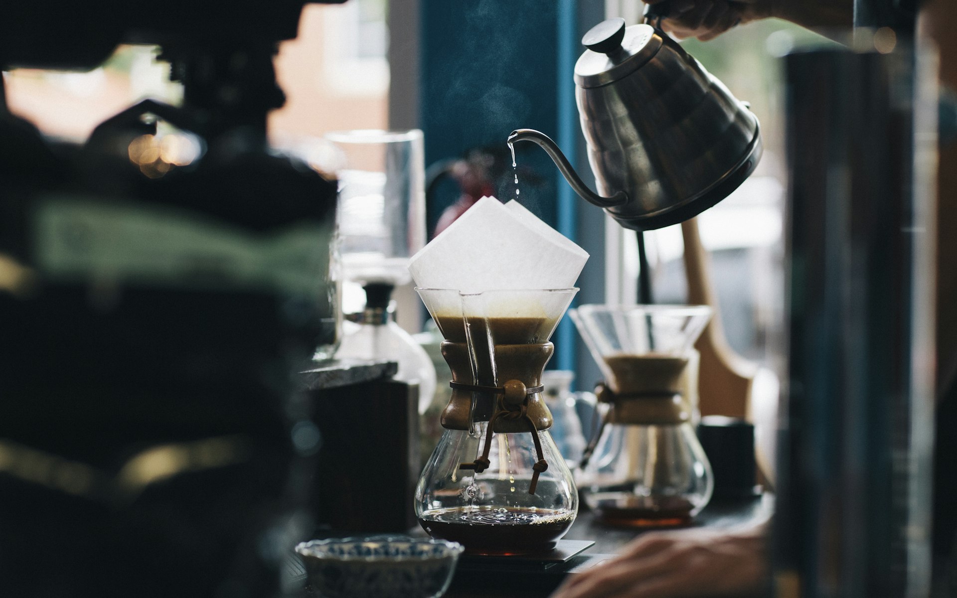 Pour-over brewing on a wooden counter in warm light
